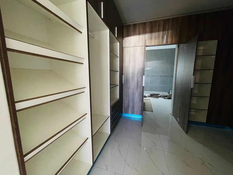 Modern walk-in closet featuring extensive built-in cabinetry with integrated LED lighting and high-gloss marble-look floor tiles.