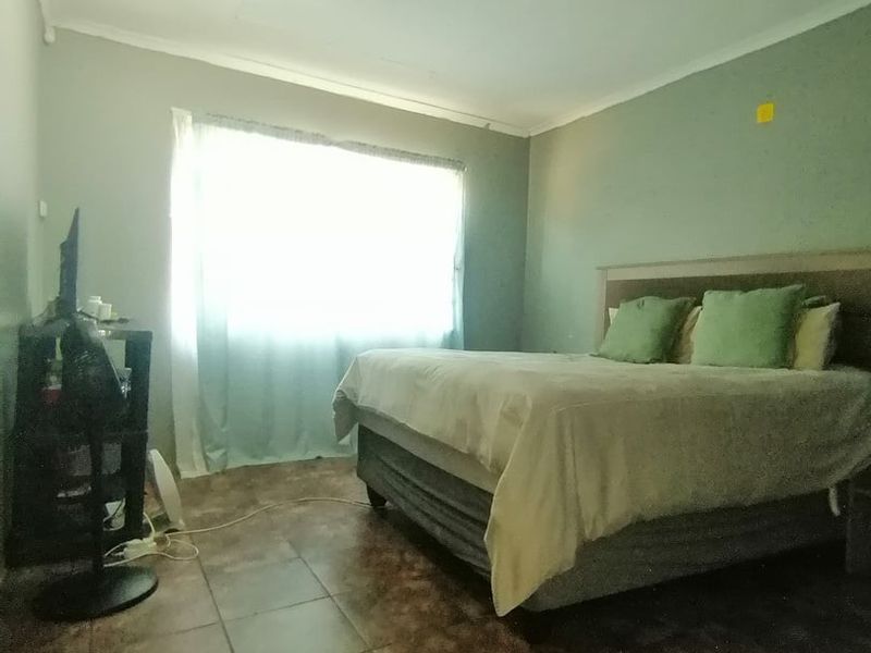 A bedroom featuring tiled flooring and a coved ceiling, providing a functional space with natural light from the window.