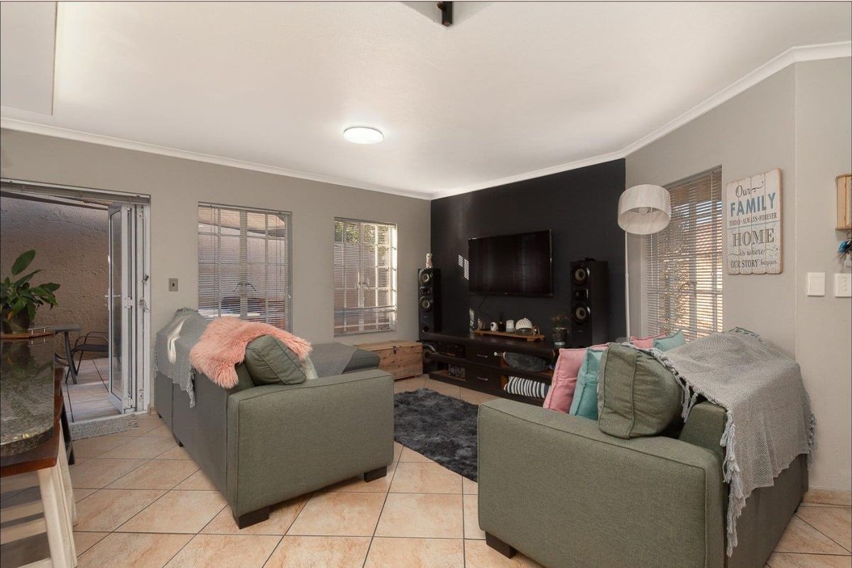 A comfortable living room featuring tiled flooring, neutral wall tones, and a feature wall, with direct access to an outdoor patio area.