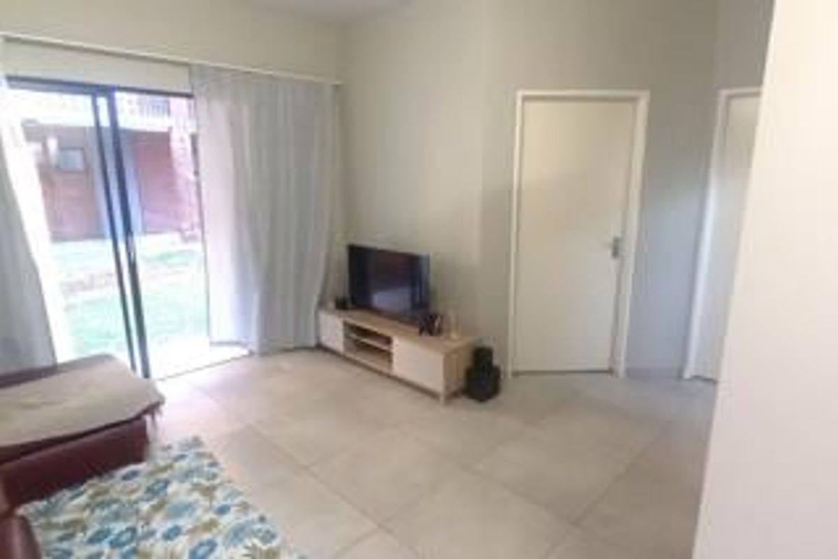 A living room featuring tiled flooring and a sliding glass door providing access to the exterior area.
