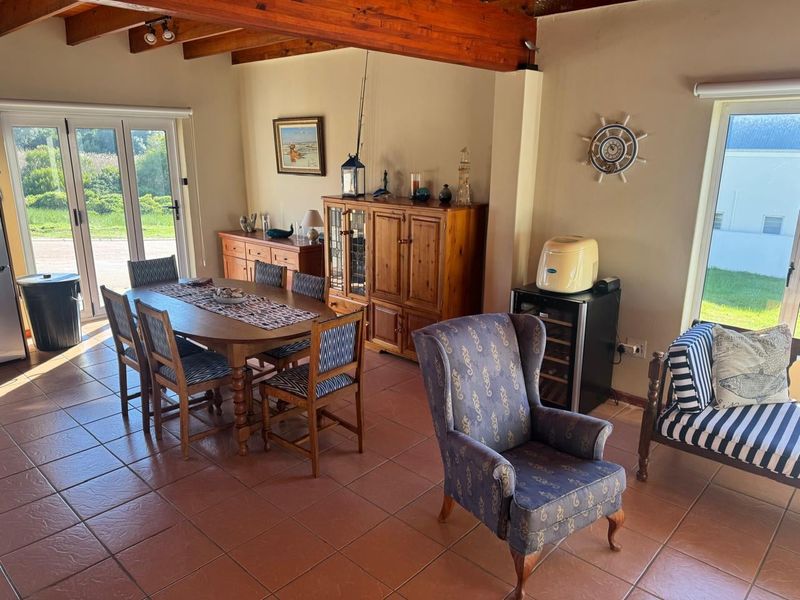 Dining area featuring exposed timber ceiling beams, terracotta floor tiles, and double glass sliding doors providing access to the exterior.