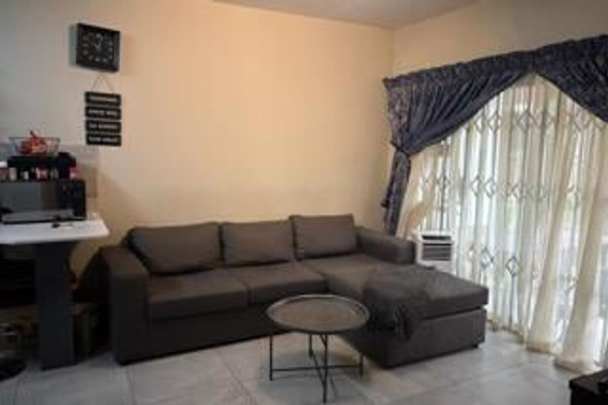 A living room featuring tiled flooring and a sliding glass door with a security gate, providing access to the exterior.