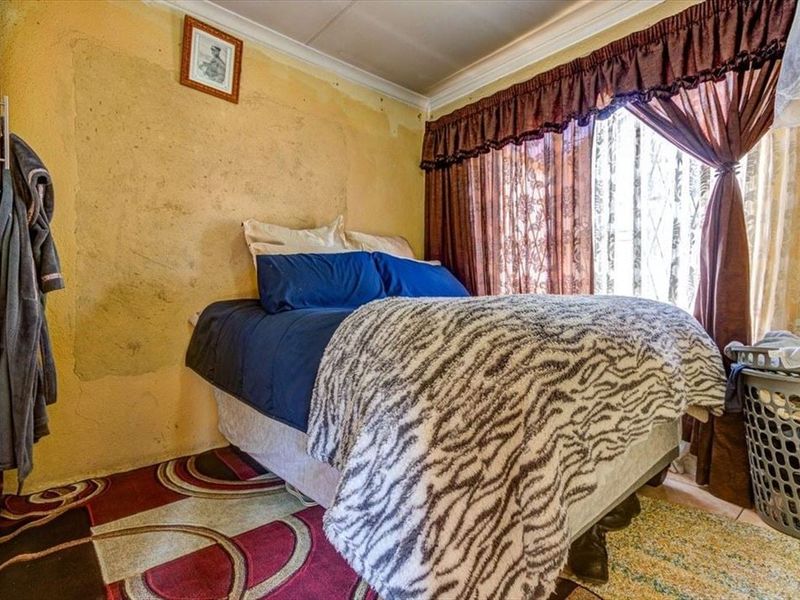 A bedroom featuring a built-in wardrobe and coving, currently requiring significant wall repairs and cosmetic updates to improve the overall finish.