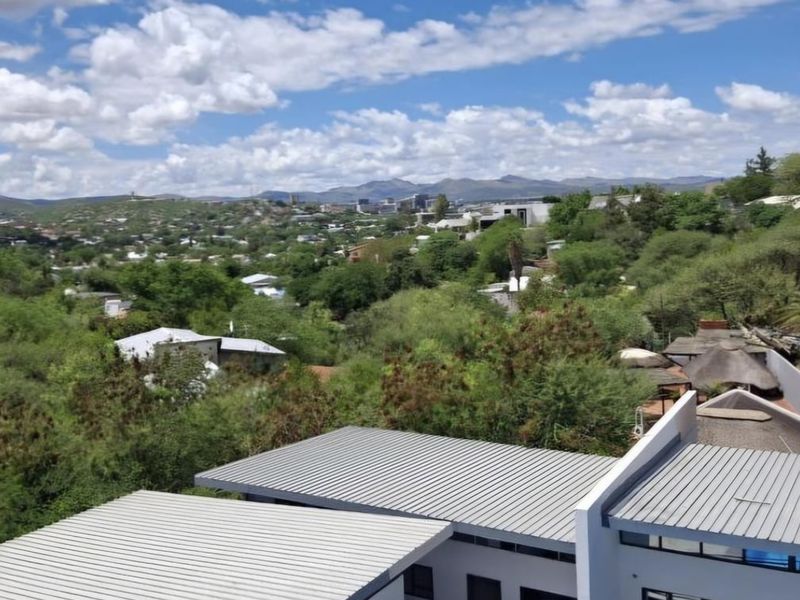 Elevated view overlooking the surrounding neighbourhood and landscape, featuring modern building roof structures in the foreground.