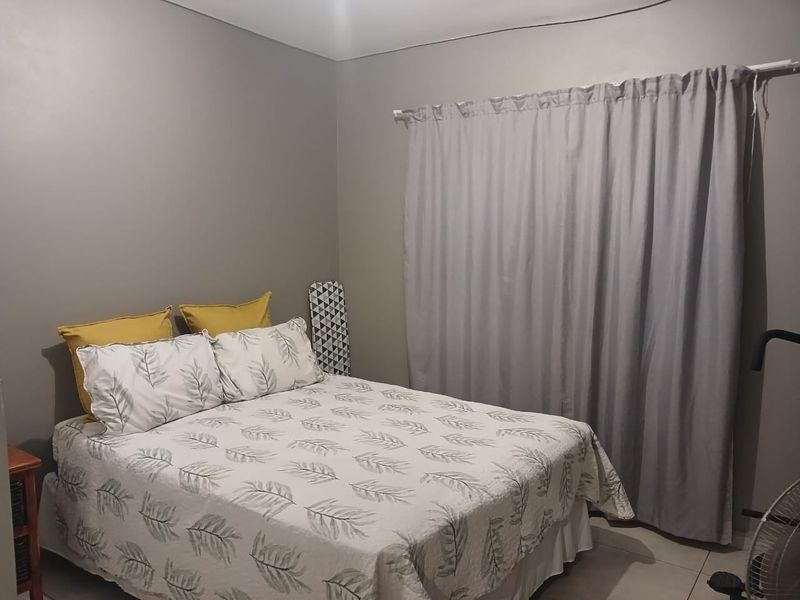 A functional bedroom featuring neutral wall tones and a window fitted with a curtain rail.