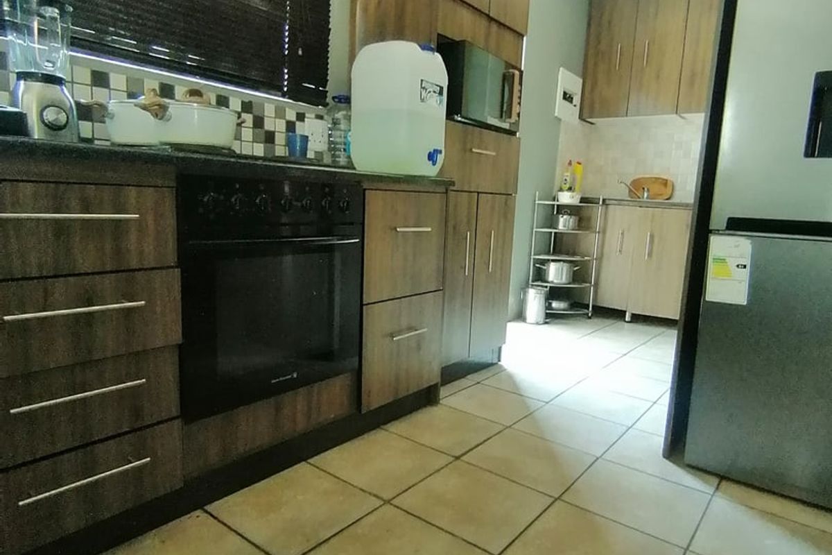 A functional kitchen featuring wood-finish cabinetry, built-in oven, tiled flooring, and a tiled backsplash, offering a practical layout for daily meal preparation.