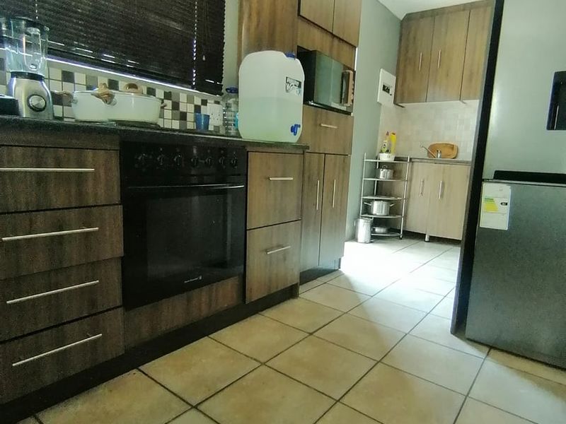 A functional kitchen featuring wood-finish cabinetry, built-in oven, tiled flooring, and a tiled backsplash, offering a practical layout for daily meal preparation.