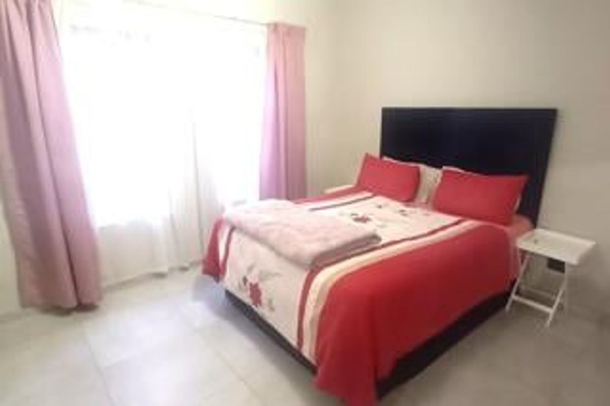 A bedroom featuring tiled flooring and a sliding glass door with curtains, providing natural light and access to the exterior.