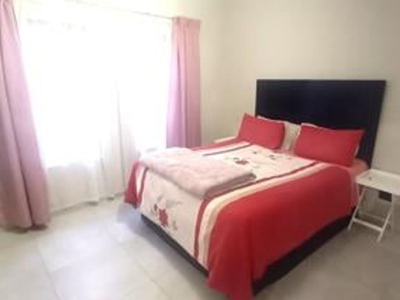 A bedroom featuring tiled flooring and a sliding glass door with curtains, providing natural light and access to the exterior.