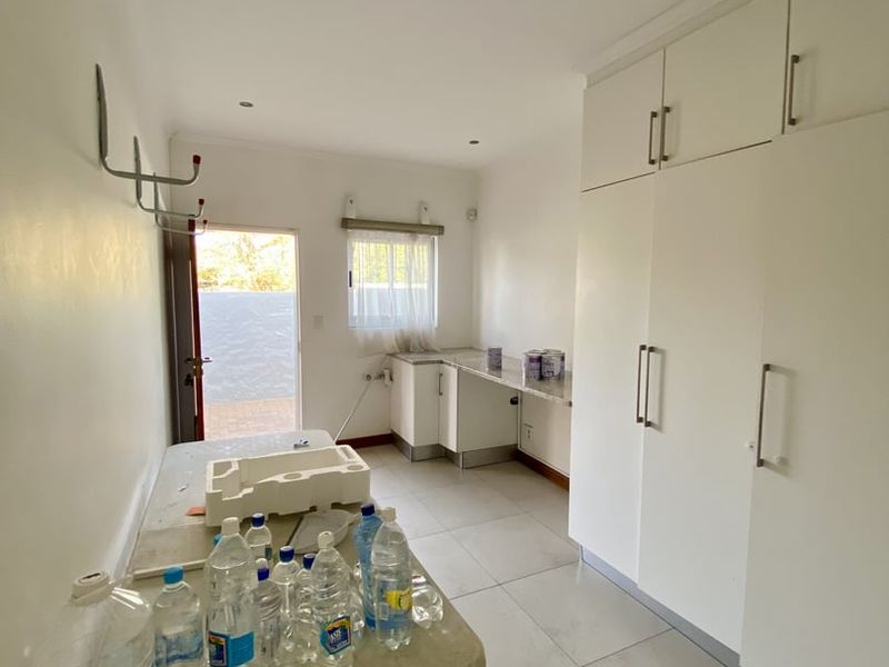 A functional laundry room featuring ample built-in cabinetry, stone countertops, tiled flooring, and direct access to the exterior.