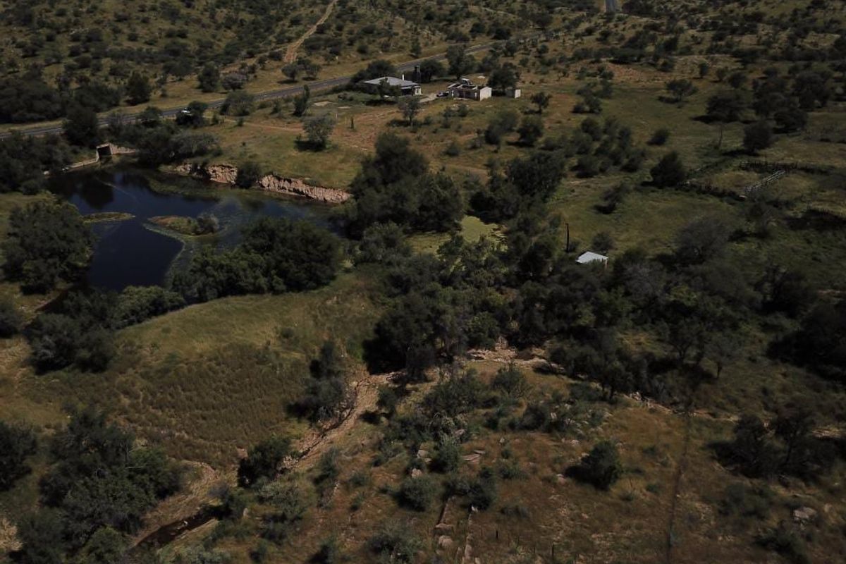 Aerial view of the farm property featuring expansive natural landscape, a dam, and access to the main road.
