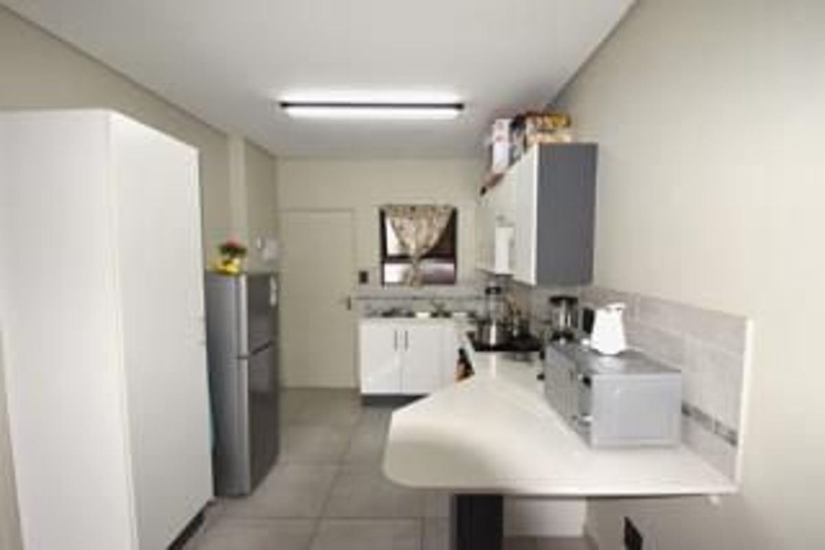A functional kitchen featuring built-in cabinetry, tiled flooring, and a breakfast bar counter, providing a practical workspace for daily meal preparation.
