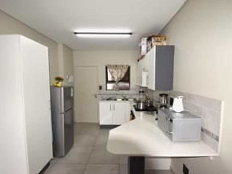 A functional kitchen featuring built-in cabinetry, tiled flooring, and a breakfast bar counter, providing a practical workspace for daily meal preparation.