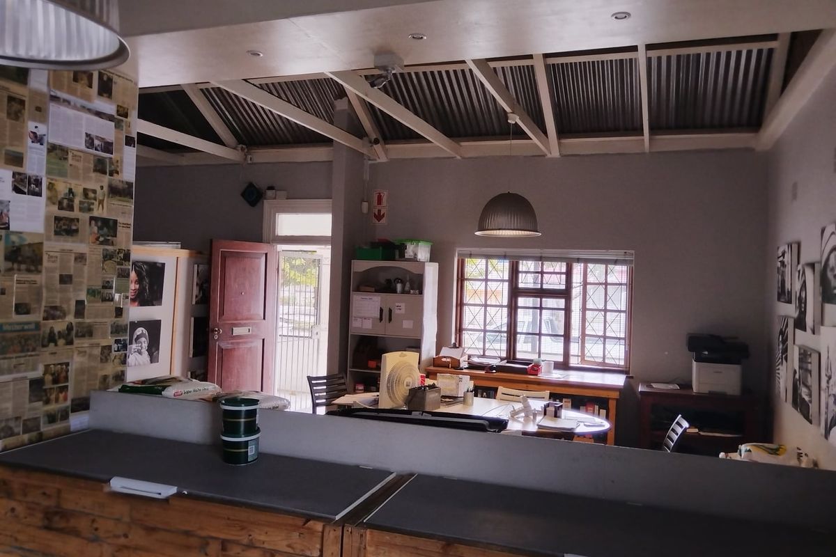 Open plan living area featuring exposed timber rafters, corrugated metal ceiling, and lattice windows, offering a versatile space with potential for modernization.