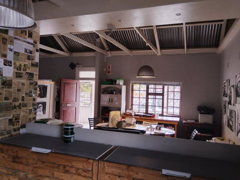 Open plan living area featuring exposed timber rafters, corrugated metal ceiling, and lattice windows, offering a versatile space with potential for modernization.