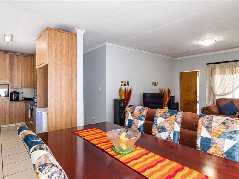 Open-plan living and dining area featuring a functional kitchen with built-in cabinetry and tiled flooring throughout the space.