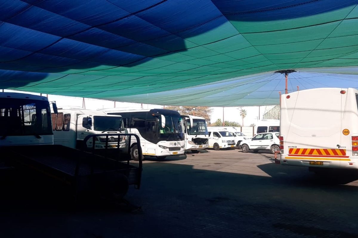 A large outdoor parking area featuring a shade cloth canopy structure, suitable for commercial vehicle storage or fleet management.