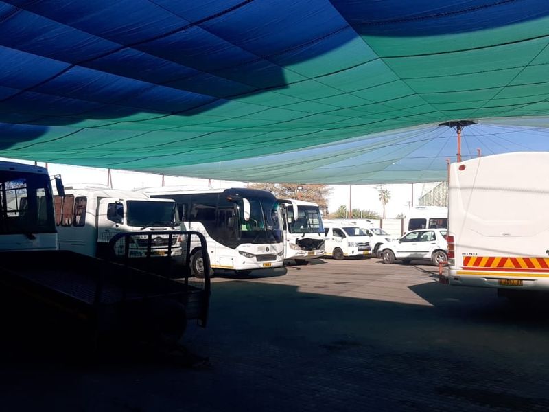A large outdoor parking area featuring a shade cloth canopy structure, suitable for commercial vehicle storage or fleet management.