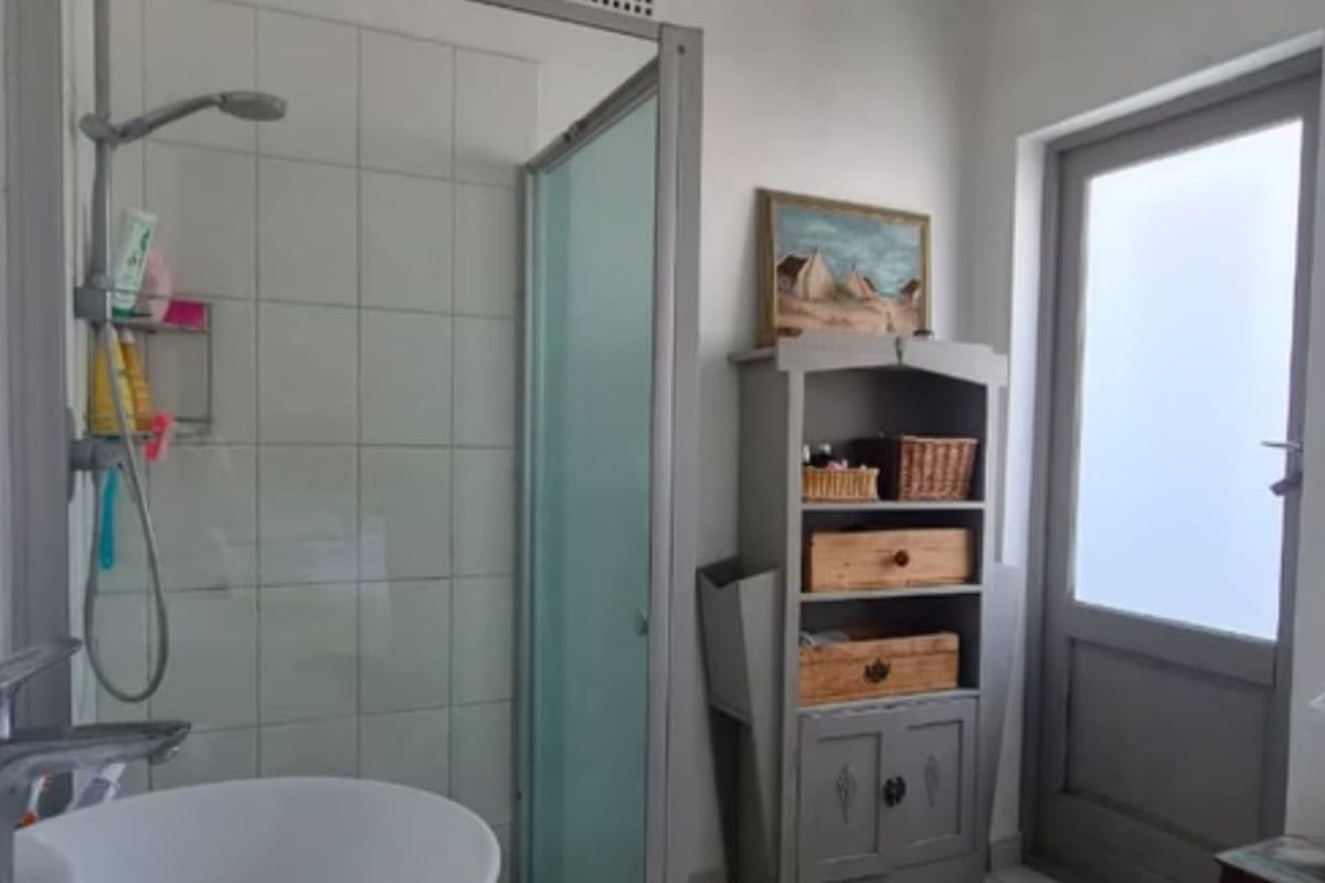 A functional bathroom featuring a shower enclosure with tiled walls, a modern basin, and a frosted glass door providing natural light.