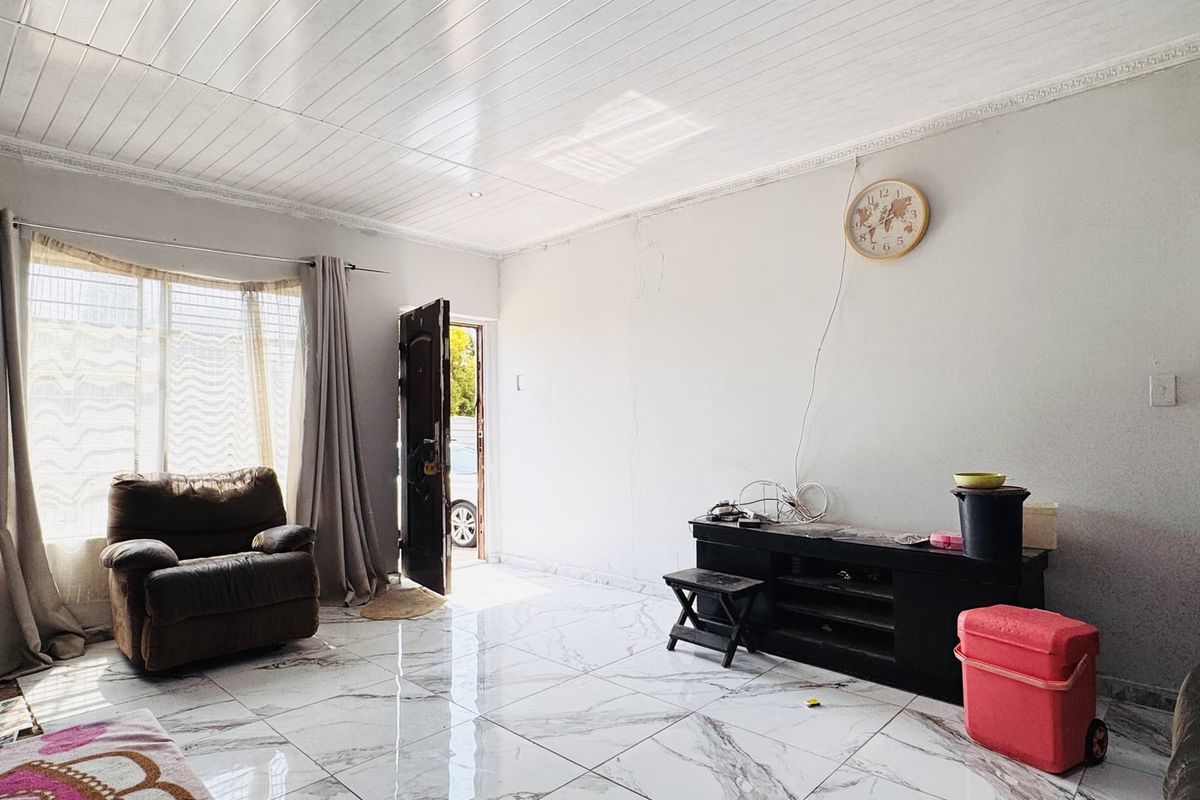 Living room featuring large marble-look floor tiles, a tongue and groove ceiling with decorative cornicing, and a bay window allowing natural light.