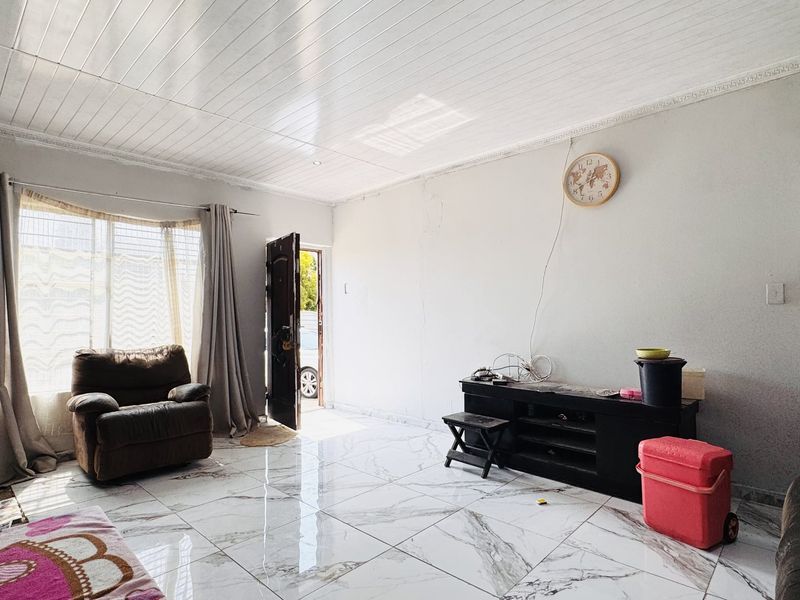 Living room featuring large marble-look floor tiles, a tongue and groove ceiling with decorative cornicing, and a bay window allowing natural light.