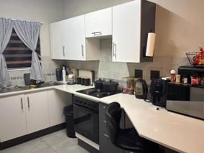 A functional kitchen featuring modern white and dark grey cabinetry, integrated electric stove and oven, and ample countertop workspace.