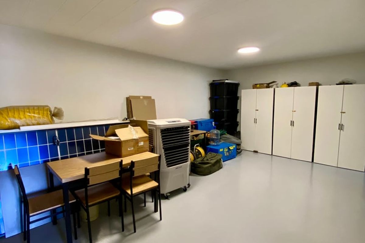 A clean utility or storage space featuring durable epoxy flooring, built-in white cabinetry, and functional ceiling lighting.