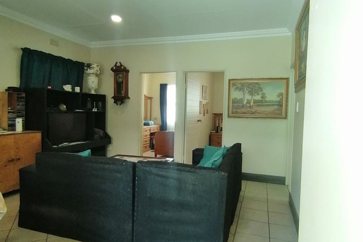 A living room area featuring tiled flooring, recessed lighting, and coved ceiling cornices, providing access to adjacent rooms.