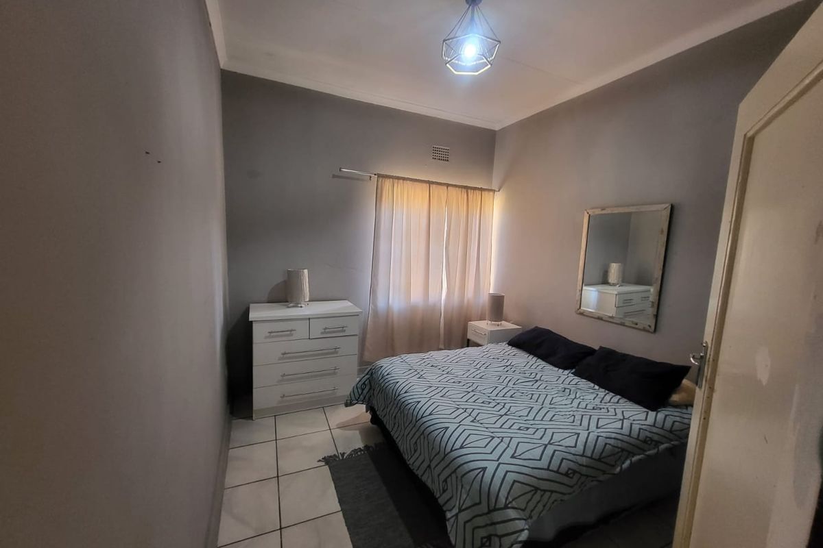 A standard bedroom featuring tiled flooring, neutral wall paint, and a central ceiling light fixture.