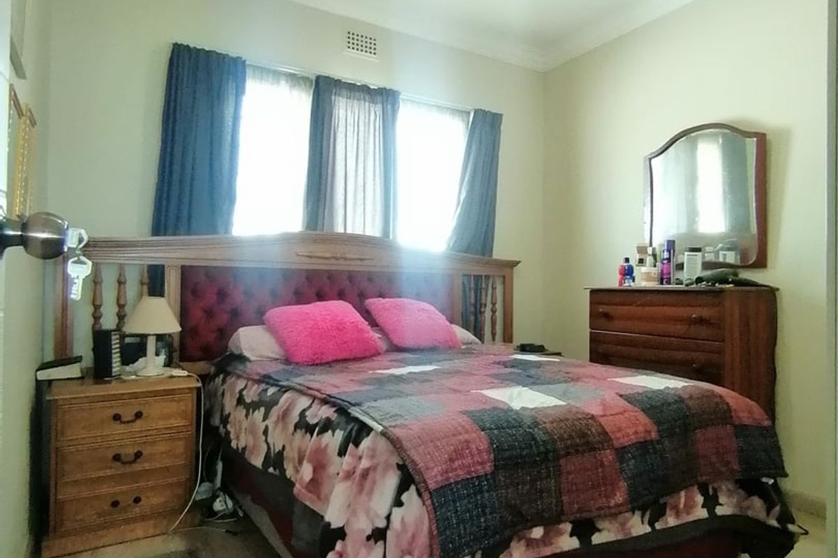 A standard bedroom featuring neutral wall paint, crown molding, and a ventilation grille, providing a functional space for rest.