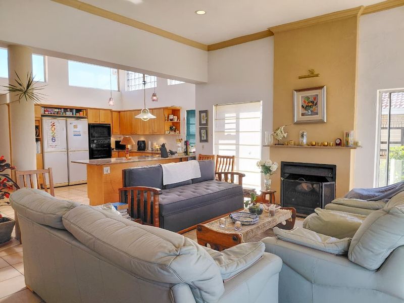 Spacious open-plan living area featuring a built-in fireplace and a functional kitchen with wooden cabinetry and a central island.
