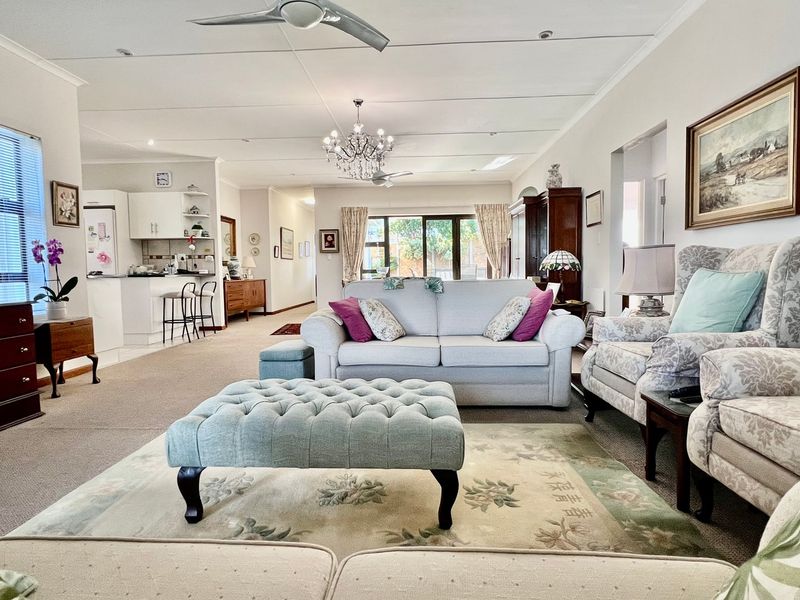 Spacious open-plan living area featuring a kitchen with island, dining space, and lounge area with direct access to the garden through sliding glass doors.
