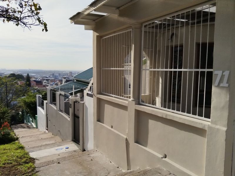 Front exterior view of the property featuring a concrete staircase, security bars on windows, and a view overlooking the surrounding neighborhood.