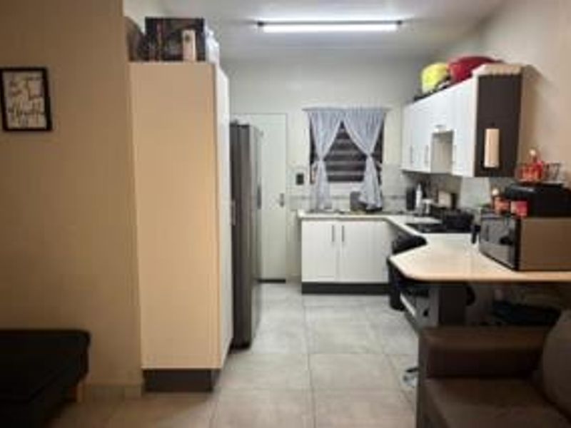 Open plan kitchen and living area featuring tiled flooring, built-in cabinetry, and laminate countertops in a functional layout.