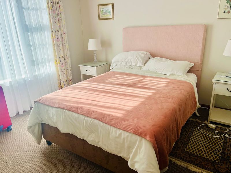 A well-lit bedroom featuring neutral wall finishes and carpeted flooring, providing a comfortable and functional sleeping space.