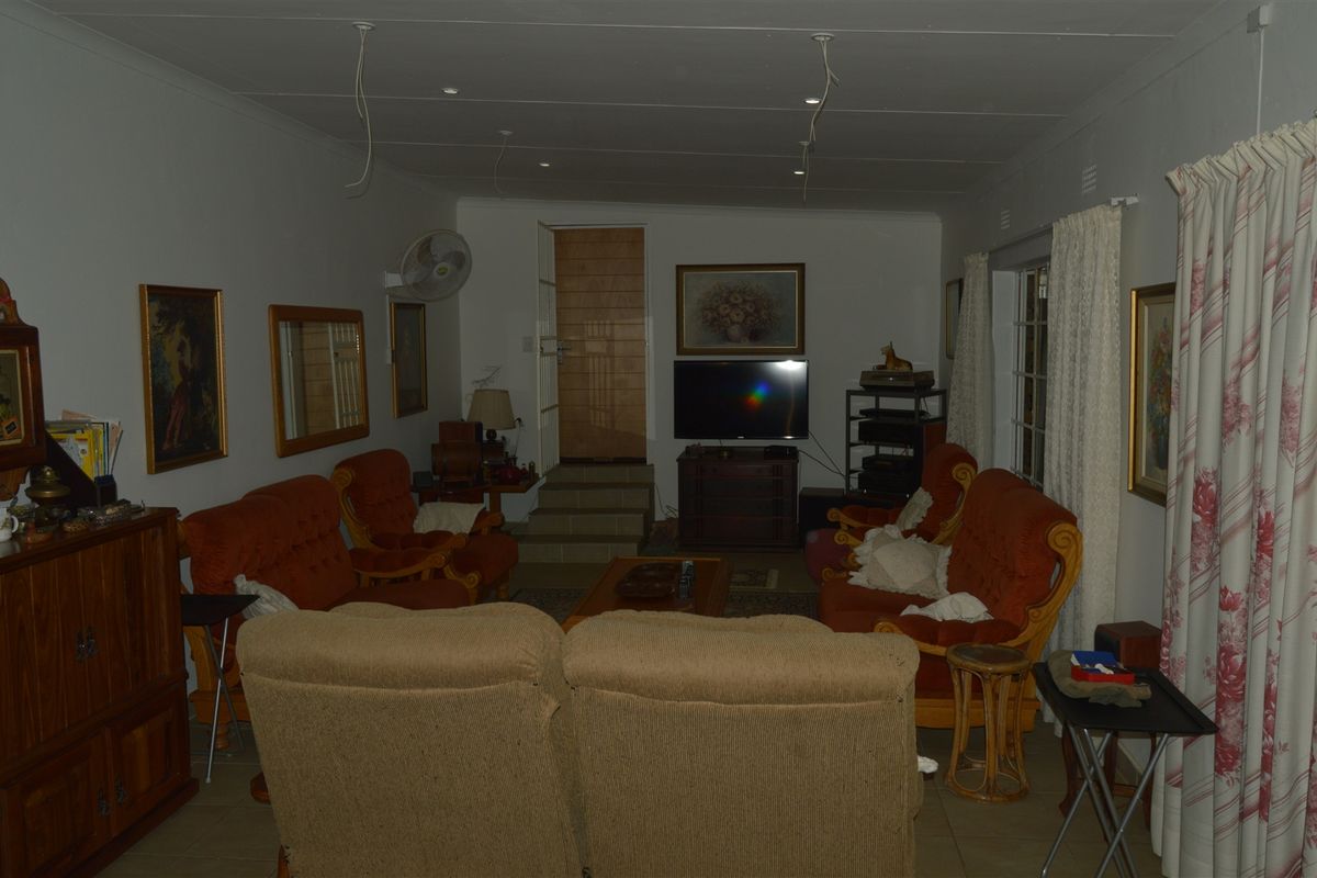 A living room featuring tiled flooring, recessed lighting, and internal steps. The space requires cosmetic updates and electrical finishing.
