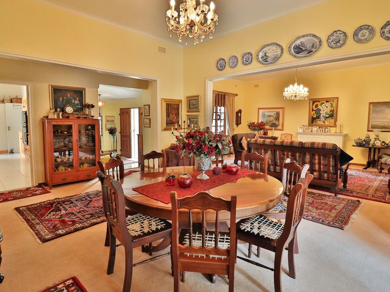 Spacious open-plan living and dining area featuring traditional architectural details, including an elegant chandelier and a classic fireplace mantel.