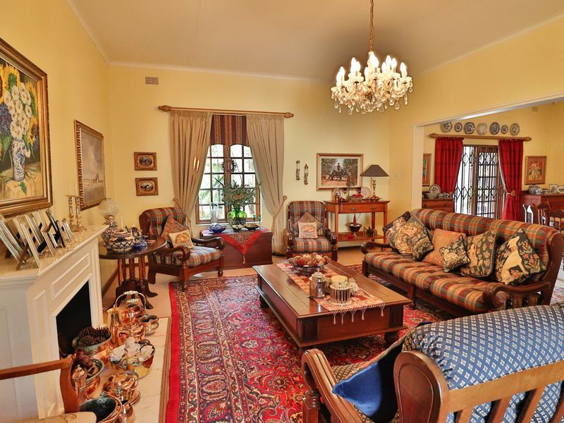 A traditional living room featuring a fireplace with a mantelpiece, a decorative chandelier, and an open-plan layout leading to the dining area.