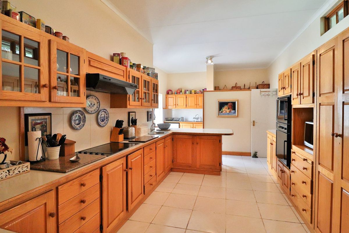 Spacious kitchen featuring extensive wooden cabinetry, built-in appliances, tiled flooring, and ample counter space, offering a functional layout with a classic aesthetic.