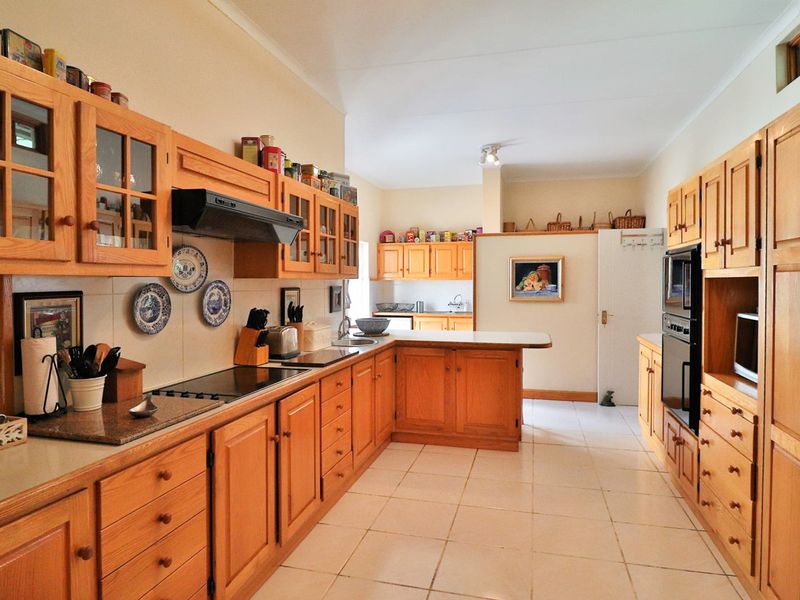 Spacious kitchen featuring extensive wooden cabinetry, built-in appliances, tiled flooring, and ample counter space, offering a functional layout with a classic aesthetic.