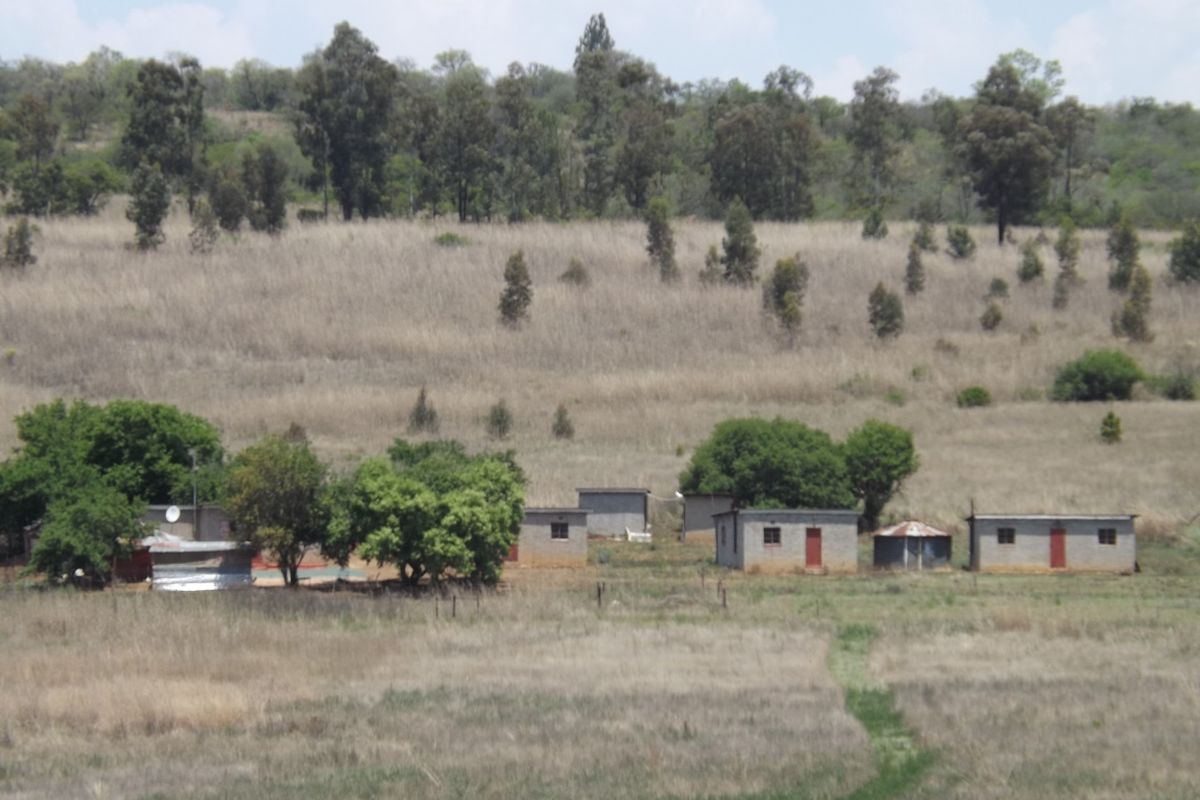 An aerial view of a rural farm property featuring multiple detached structures set within a large, open landscape.