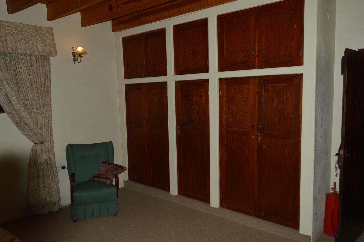 Bedroom featuring extensive built-in wooden cabinetry and exposed timber ceiling beams, offering ample storage space with a traditional aesthetic.