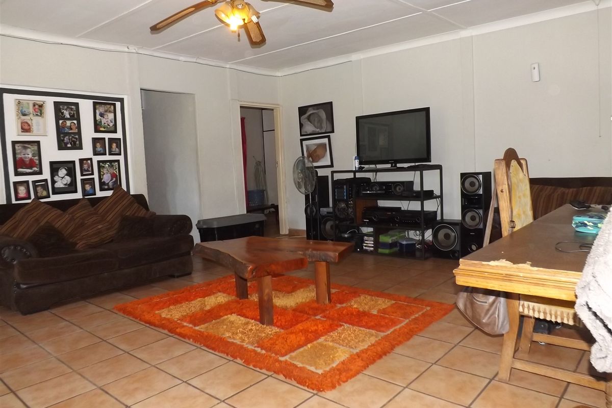 A spacious living area featuring ceramic floor tiles and a ceiling fan, providing a functional and open layout for family relaxation.