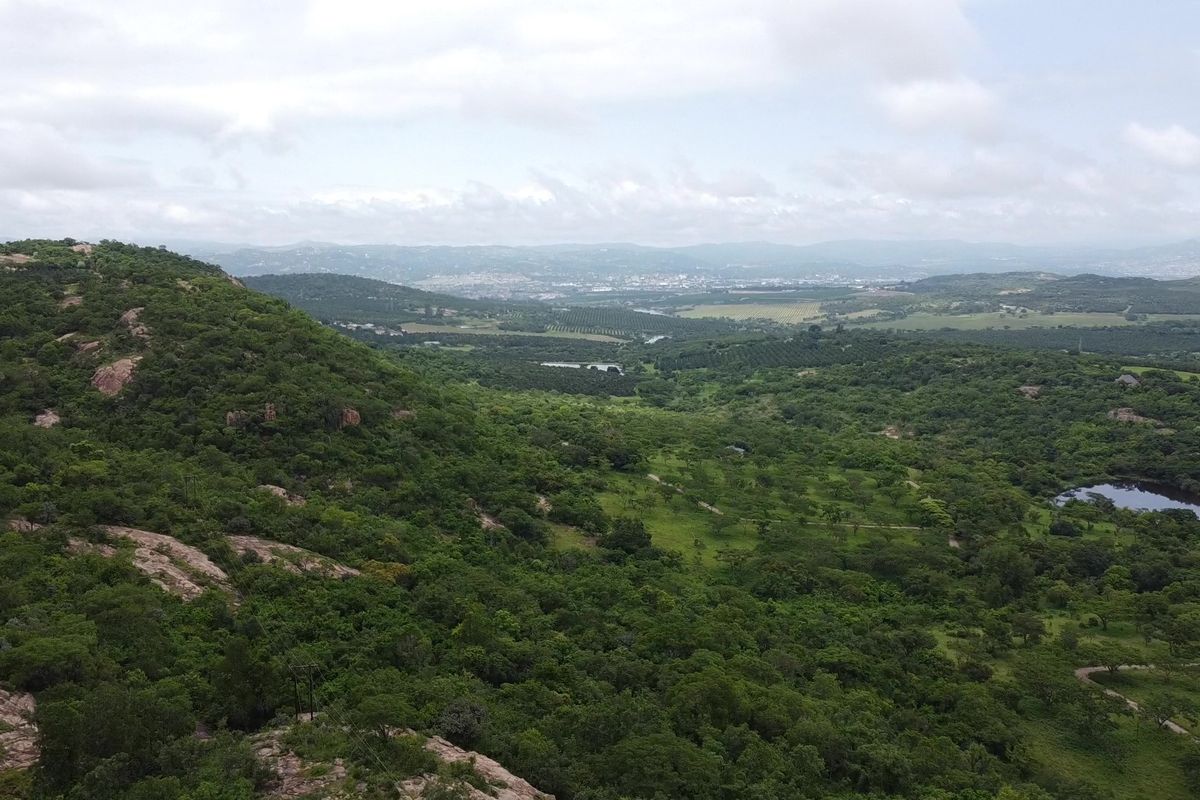 Expansive aerial landscape view overlooking lush green hills, natural vegetation, and distant valley terrain on a farm property.