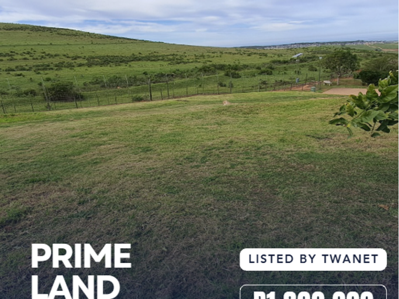 A view of a vacant residential plot featuring grassy terrain and perimeter fencing in a scenic landscape setting.