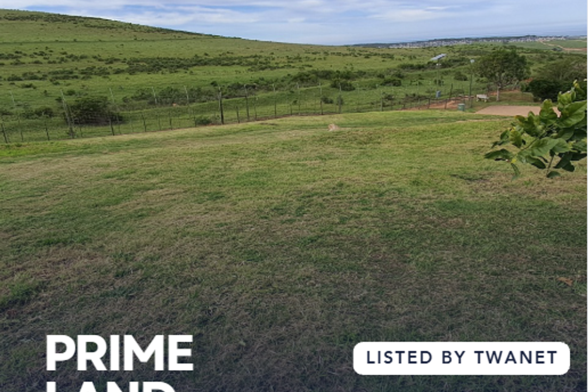 A view of a vacant residential plot featuring grassy terrain and perimeter fencing in a scenic landscape setting.
