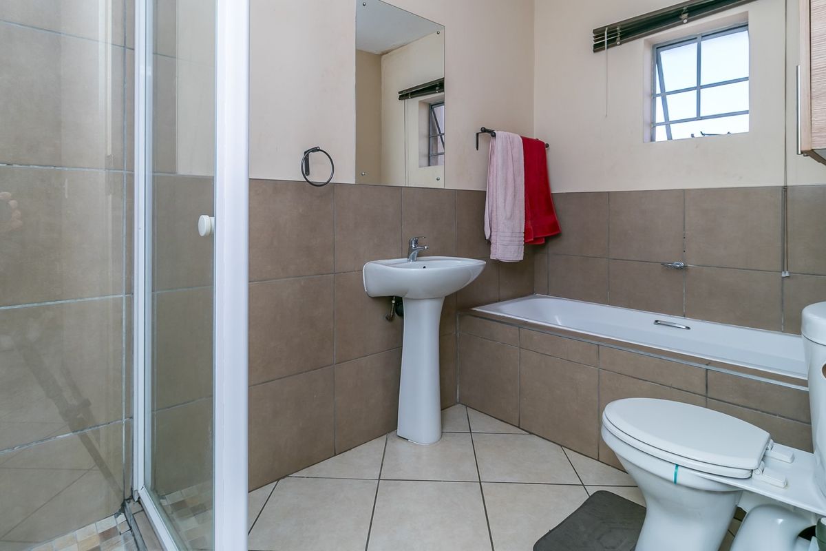 A functional bathroom featuring a pedestal basin, a built-in bathtub with tiled surround, and a separate glass-enclosed shower unit.