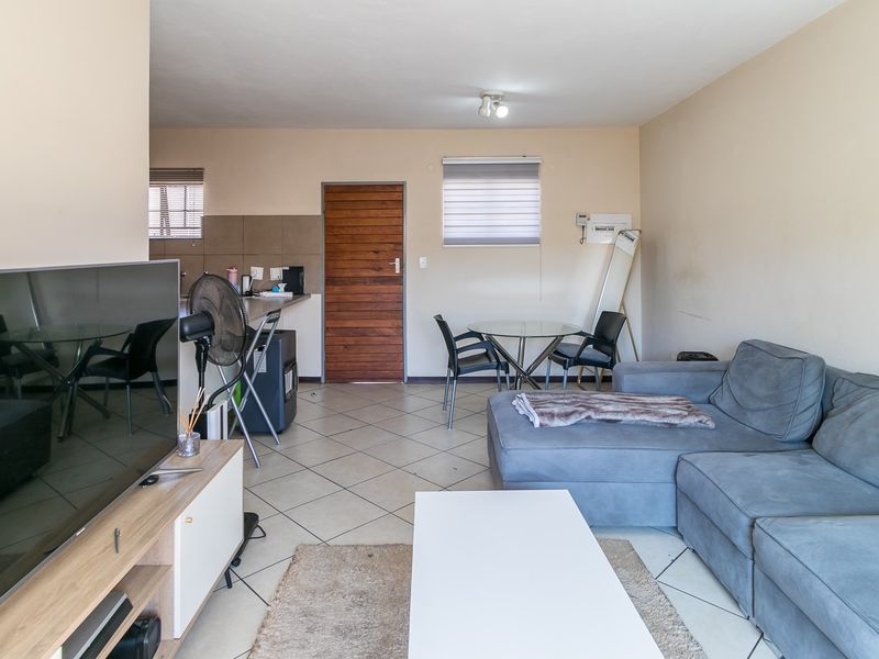 Open-plan living area featuring tiled flooring, a functional kitchen corner, and direct access to an exterior door.