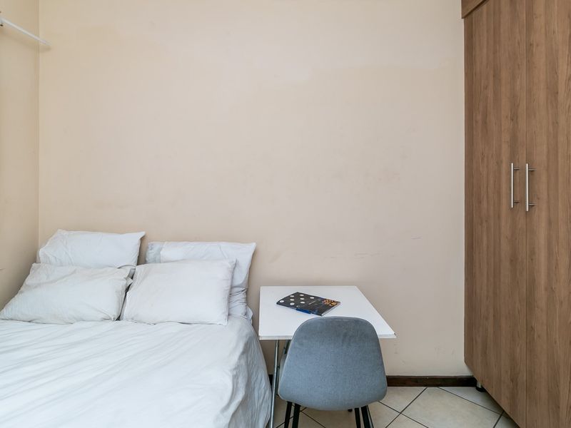 A compact bedroom featuring built-in wooden cabinetry and tiled flooring, providing a functional and efficient living space.