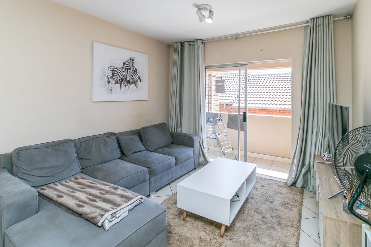 A comfortable living room featuring tiled flooring and sliding glass doors that provide direct access to a private balcony.